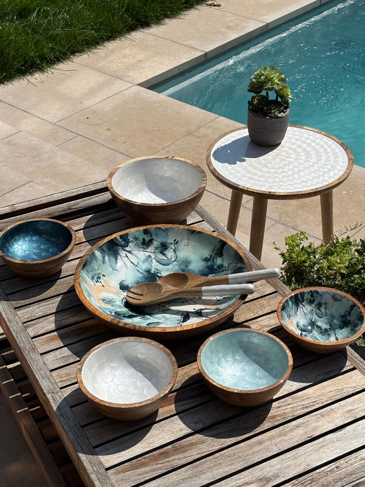 Blue marble collection and various hand-painted bowls by a swimming pool. Plus a white coffee table.