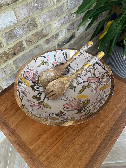Large statement bowl made from sustainable mango wood with matching salad servers. Featuring gold foil accents and magnolia flowers