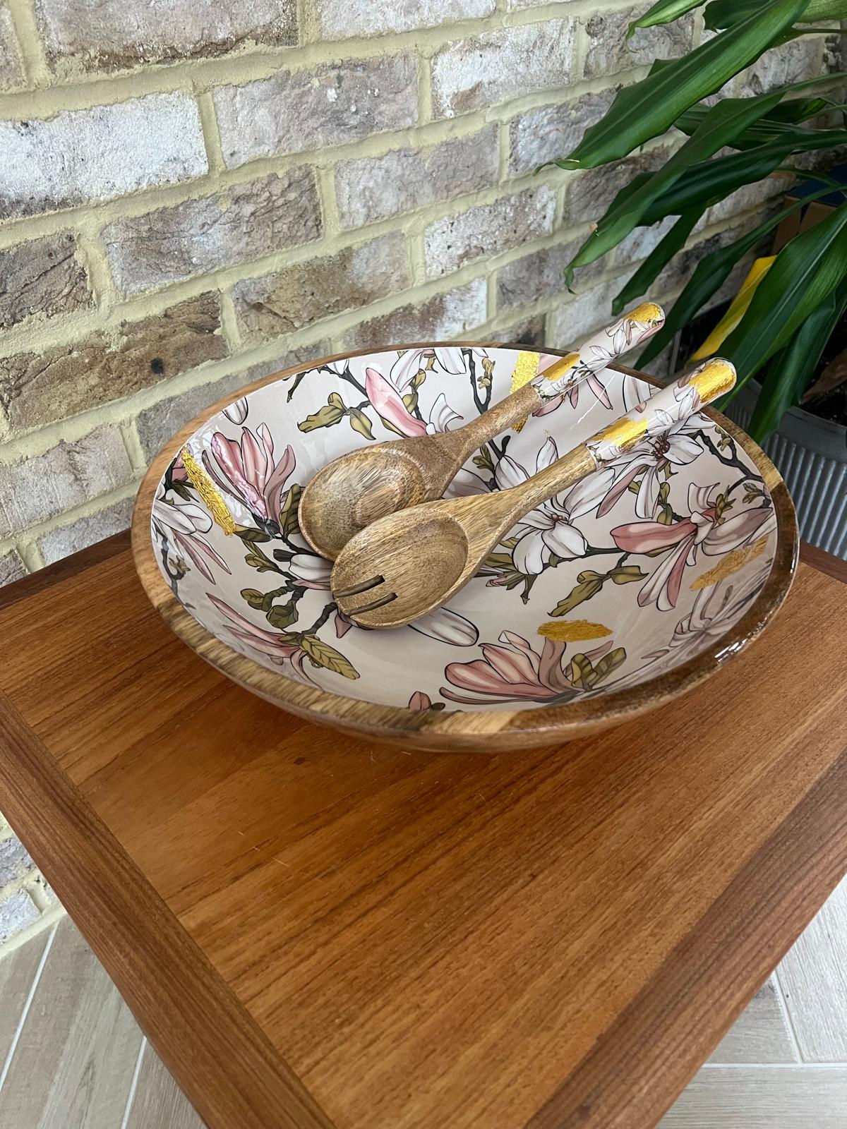 Large statement bowl made from sustainable mango wood with matching salad servers. Featuring gold foil accents and magnolia flowers