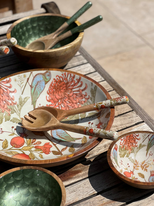 small and Large bowl with matching salad servers. Decorated with a william morris style design featuring orange and turquoise birds and pomegranates. Alongside a small and medium hand-painted bowls in olive green with matching salad servers. Fish scale design