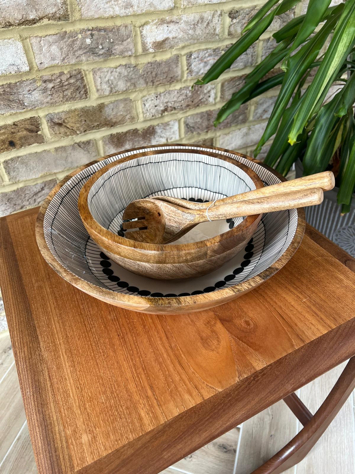 2 wooden bowls and matching salad servers.  Bowls Decorated with a black and white abstract circles design.  Medium and large sized bowls with plain salad servers.  All made form sustainable mango wood
