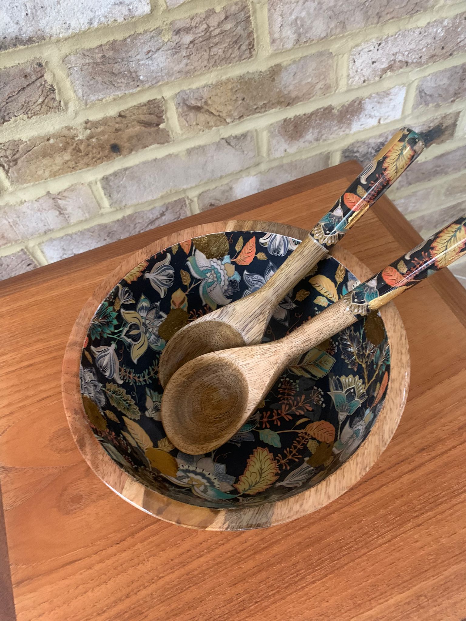 Medium sized bowl with Matching salad Servers with decorated handles. An elegant floral design in black features stunning accents of gold foil. Made from sustainable mango wood