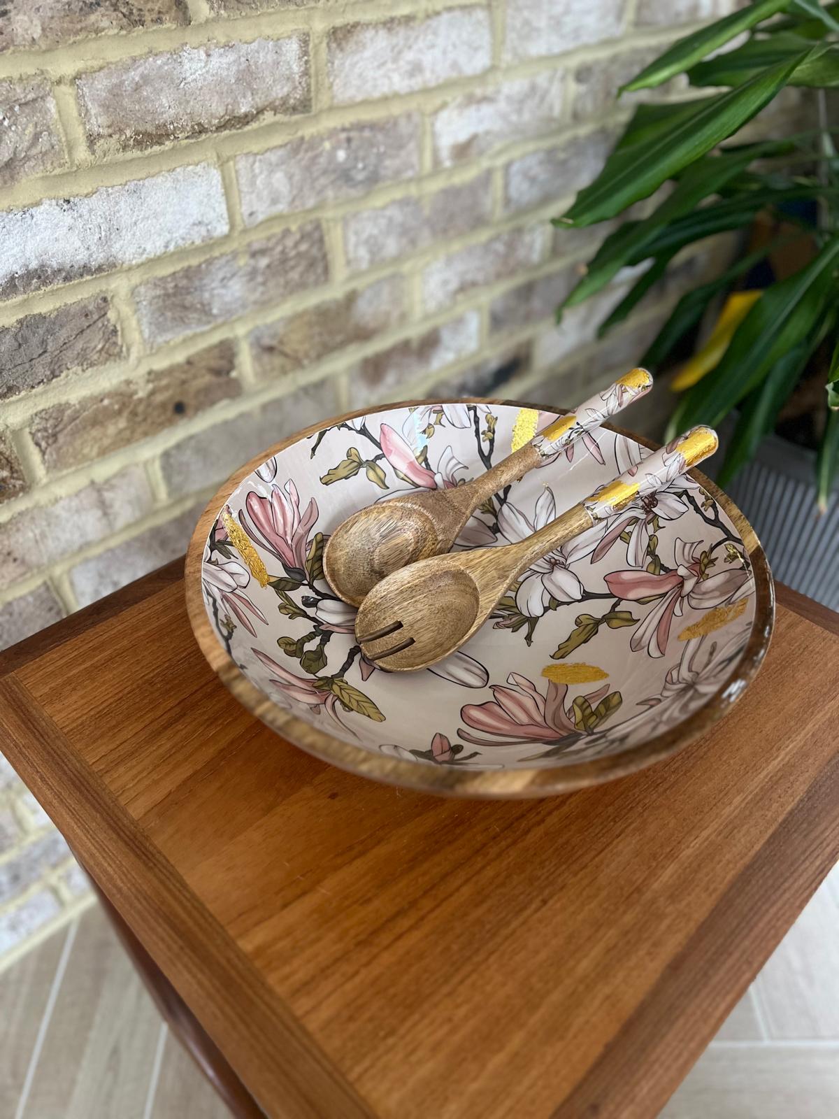 Large statement bowl made from sustainable mango wood with matching salad servers.  Featuring gold foil accents and magnolia flowers