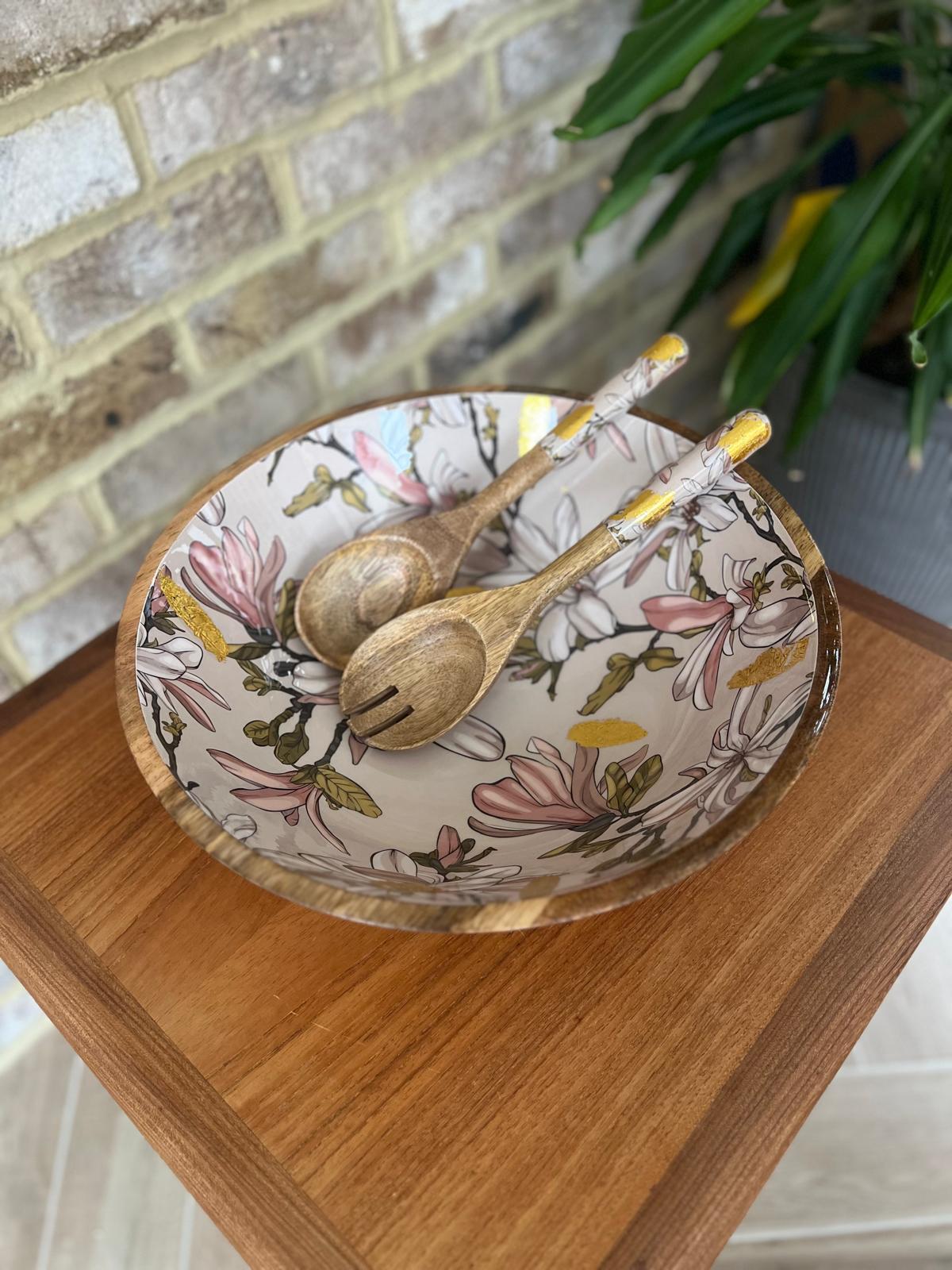 Large statement bowl made from sustainable mango wood with matching salad servers.  Featuring gold foil accents and magnolia flowers
