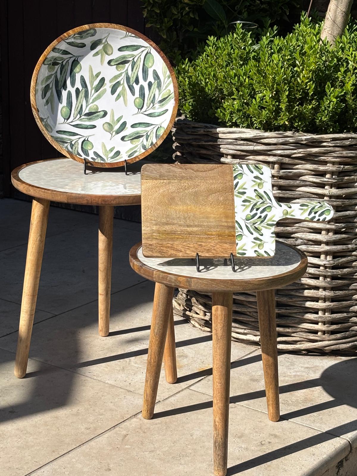 Two coffee tables with a wooden salad bowl and chopping board.  Handmade Bowl and chopping board, decorated with olive branches and olives against a white background. All made from sustainable mango wood.