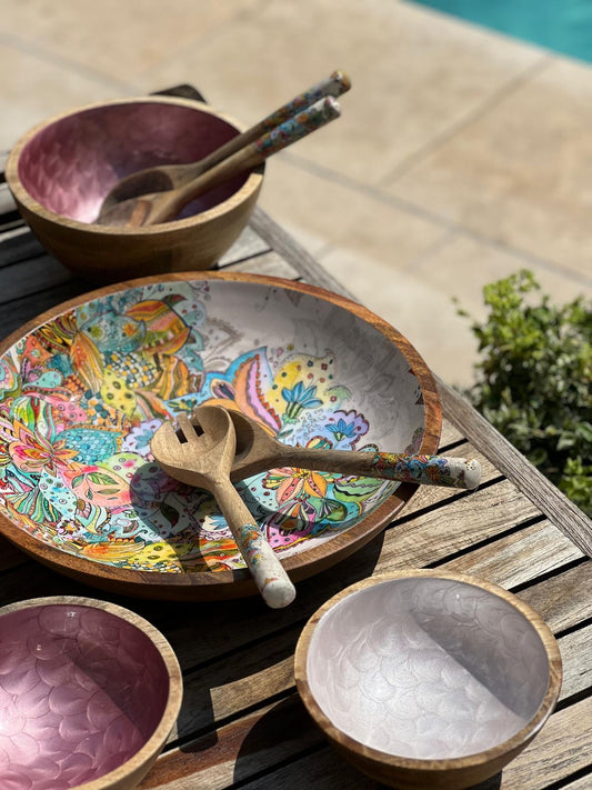 Colorful wooden bowl with multi-coloured floral design on a wooden surface outdoors.  With 3 hand-painted bowls in pinks and fish scales design